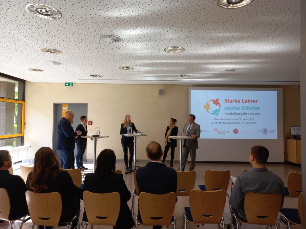 Kultusminister Lorz, Prof. Susann Gessner, Antje Scheidler und Dr. Maja Bächler s tellen gemeinsam mit Lehrkraft Valerie Sargk das Projekt vor